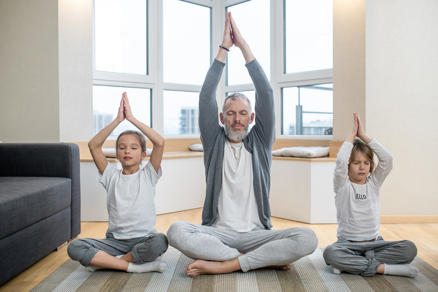 Ein Mann und zwei Kinder im Lotussitz machen Yoga in sanfter Umgebung