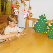 2 Kinder sitzen beim Tisch auf dem auch zwei selbstgebastelte Adventkalender stehen