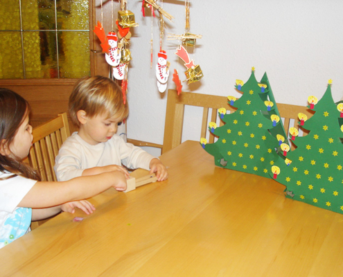 2 Kinder sitzen beim Tisch auf dem auch zwei selbstgebastelte Adventkalender stehen