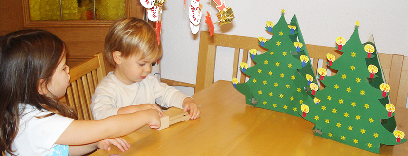 2 Kinder sitzen beim Tisch auf dem auch zwei selbstgebastelte Adventkalender stehen