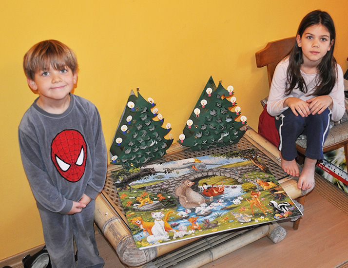 Zwei Kinder sitzen neben einem fertigen Puzzle mit 1000 Teilen