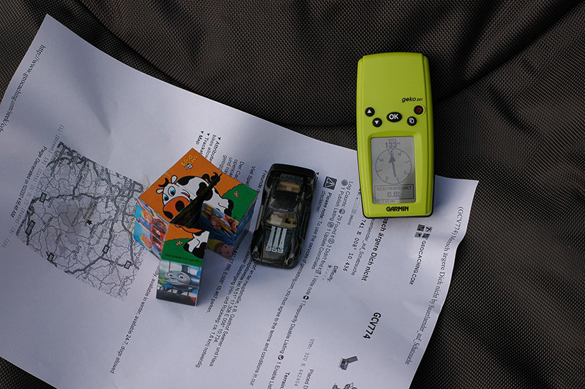 Geocaching mit GPS-Gerät mit einigen Gegenständen, die in einem Cache versteckt waren