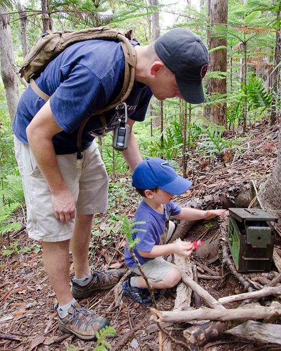 Vater mit Sohn finden einen Geocaching-Schatz im Wald